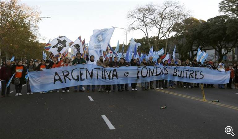 Demonstrators march to the U.S. embassy with a sign that reads "Argentina or vulture funds"